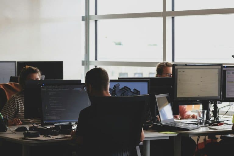 Two engineers working together in front of a computer monitor