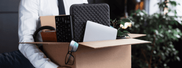 The image shows a professional with a box with his work things, symbolizing it turnover.